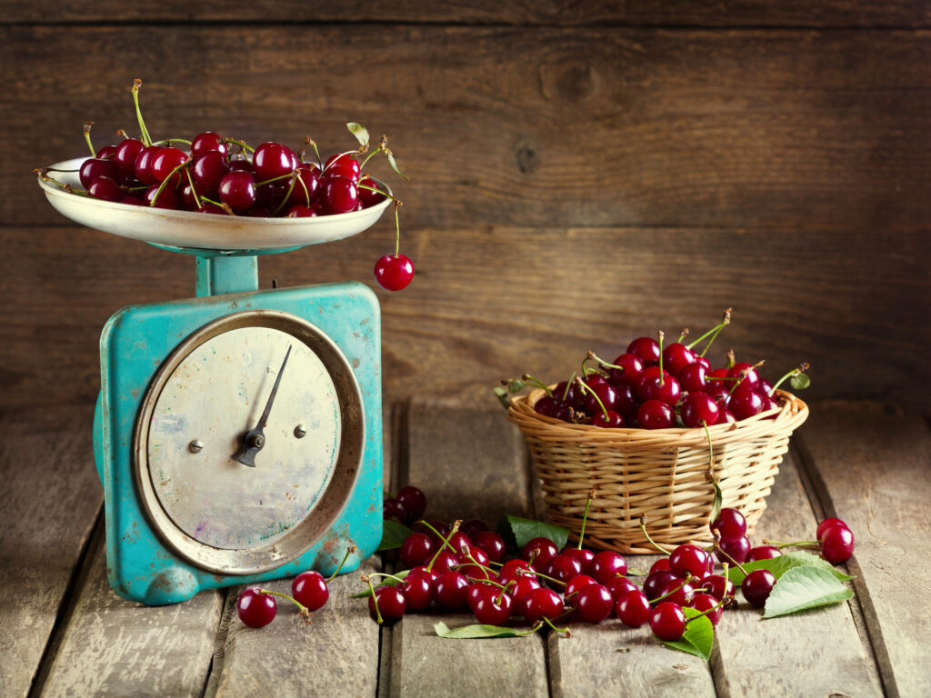 Fresh red cherries on vintage blue scale and basket on rustic wooden kitchen background Wallpaper