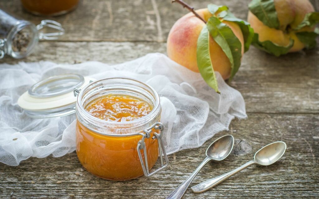 Rustic Peach Jam Display with Fresh Fruit and Vintage Crockery Wallpaper