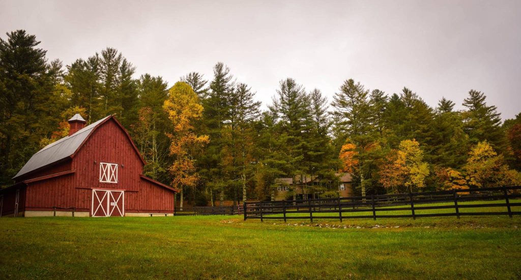 Rustic red barn with black fence green pasture autumn forest wallpaper countryside scene