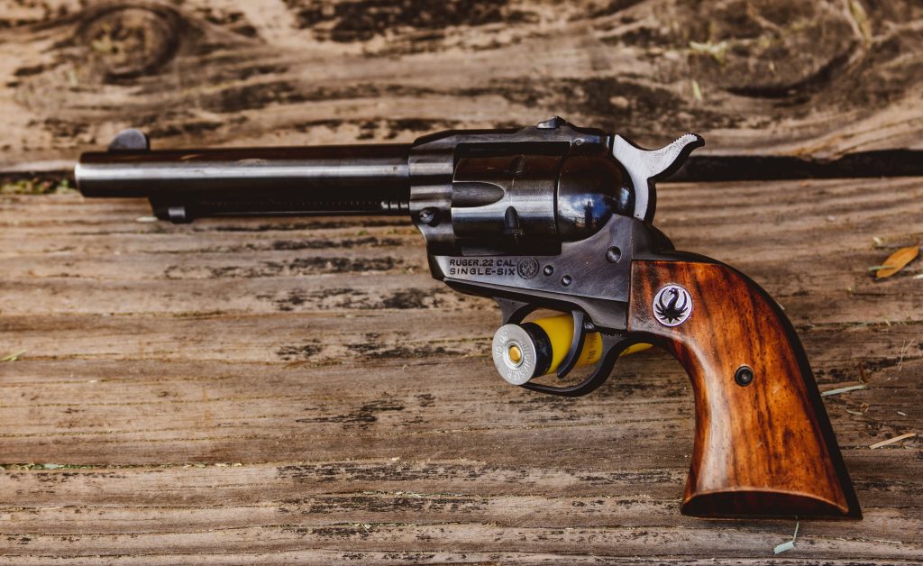 Classic Ruger Single Six revolver with yellow Winchester shell on weathered wood background Wallpaper