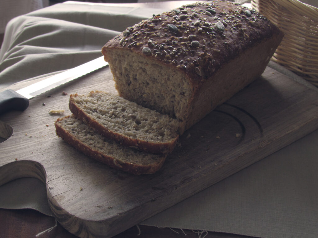 Rustic Seeded Bread Loaf on Wooden Board - Textured Delight Wallpaper