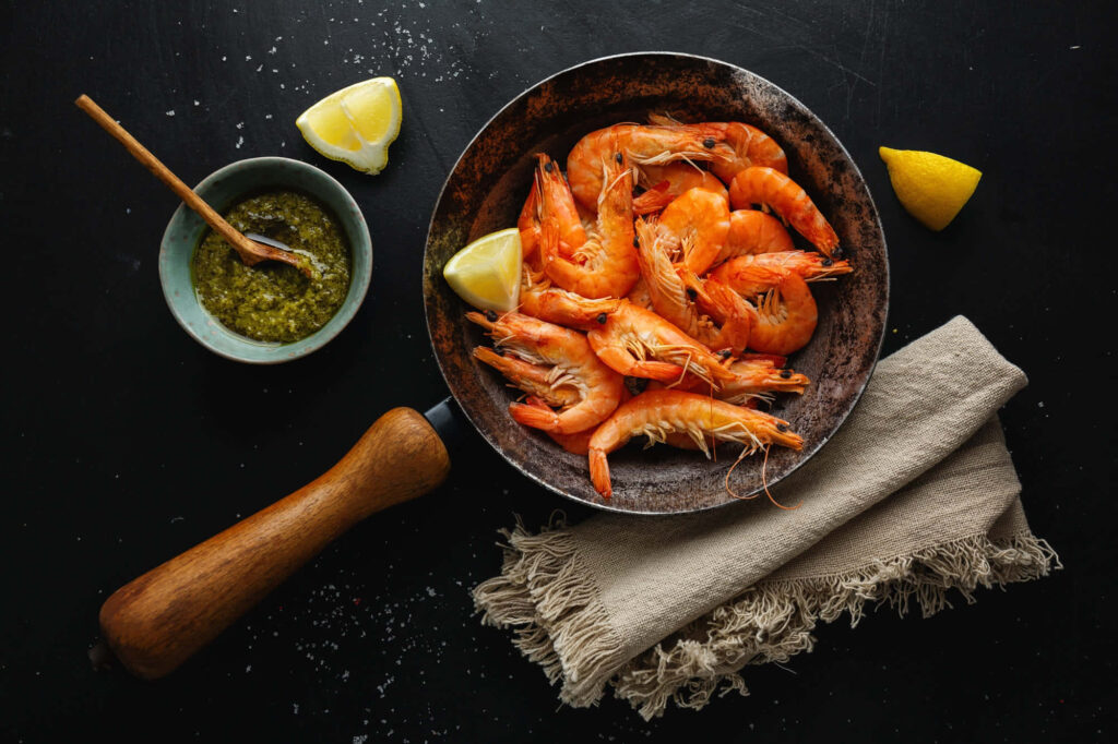 Rustic Shrimp Tabletop: Lemon Garnish & Green Sauce on Dark Wallpaper