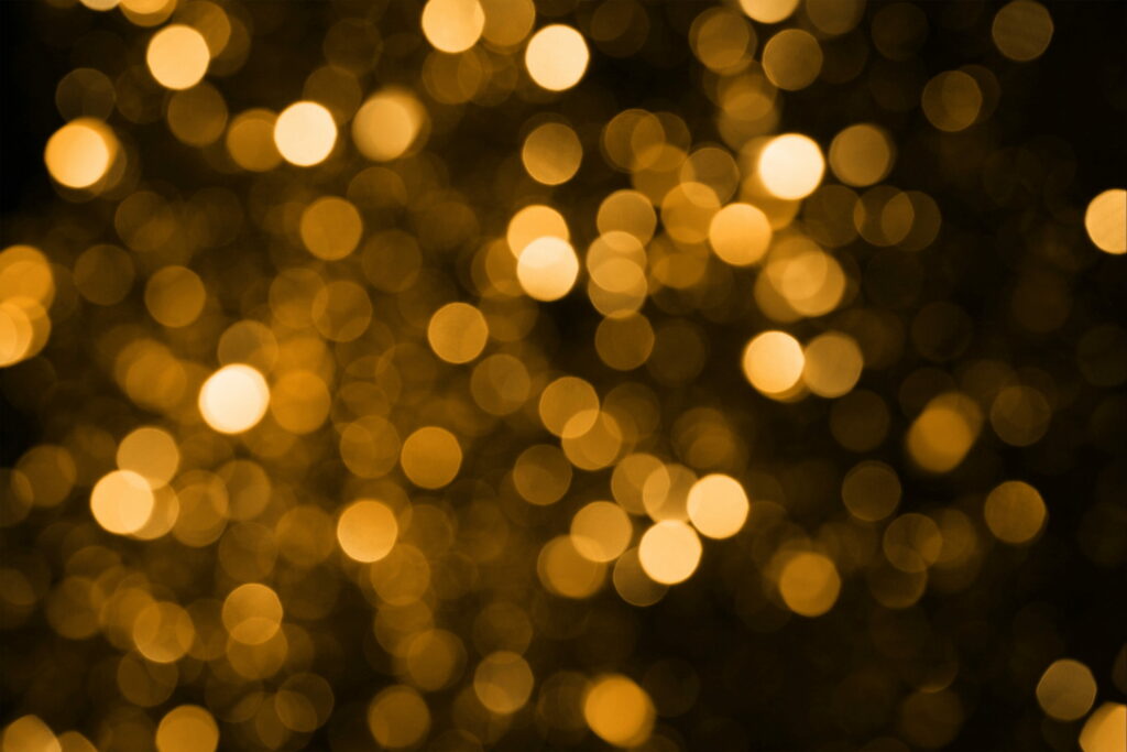 Warm golden and amber bokeh lights on dark textured background for cozy abstract wallpaper