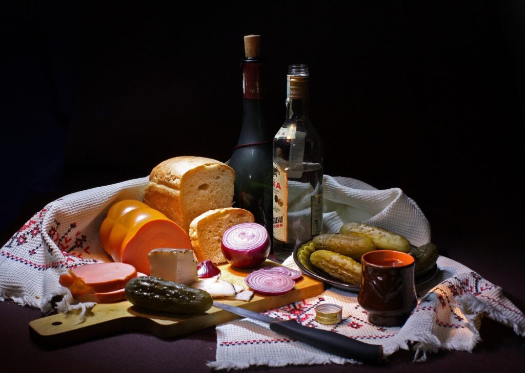 Rustic Still Life: Bread, Pickles & Sausages on Decorative Tablecloth Wallpaper