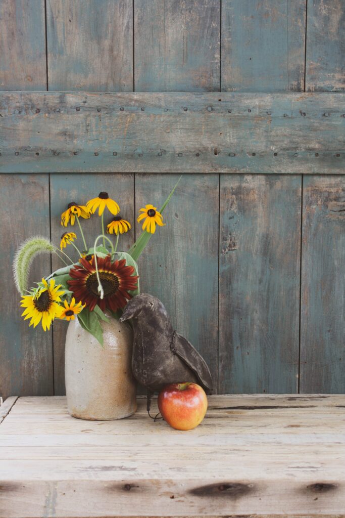 Rustic Still Life: Vibrant Flowers, Apple & Bird on Weathered Wood Wallpaper