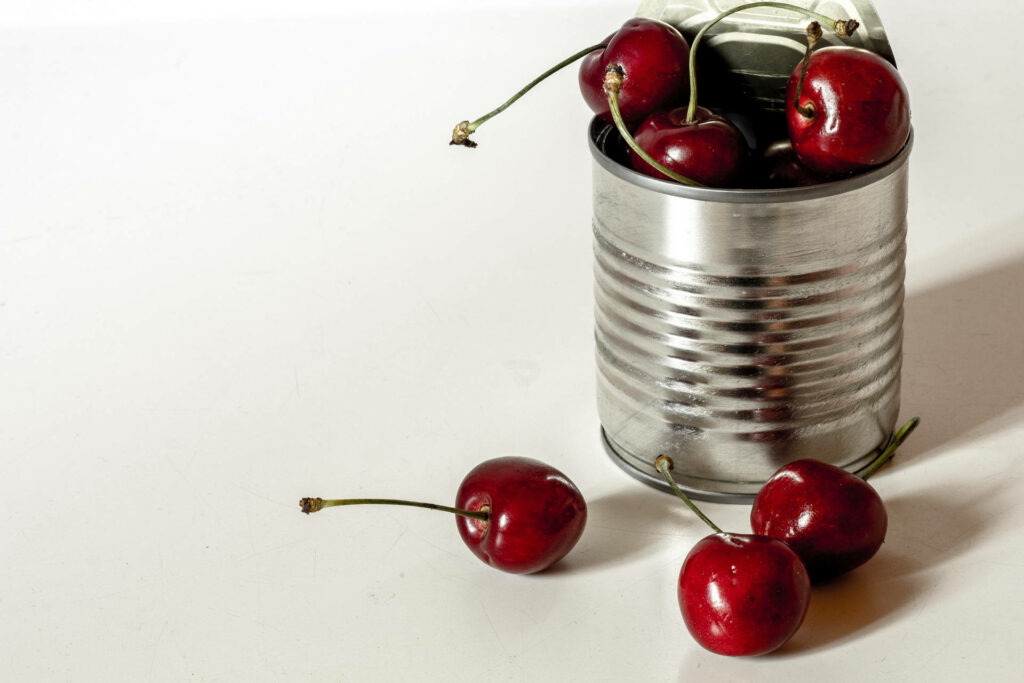Rustic tin can filled with fresh red cherries on white background vibrant still life wallpaper