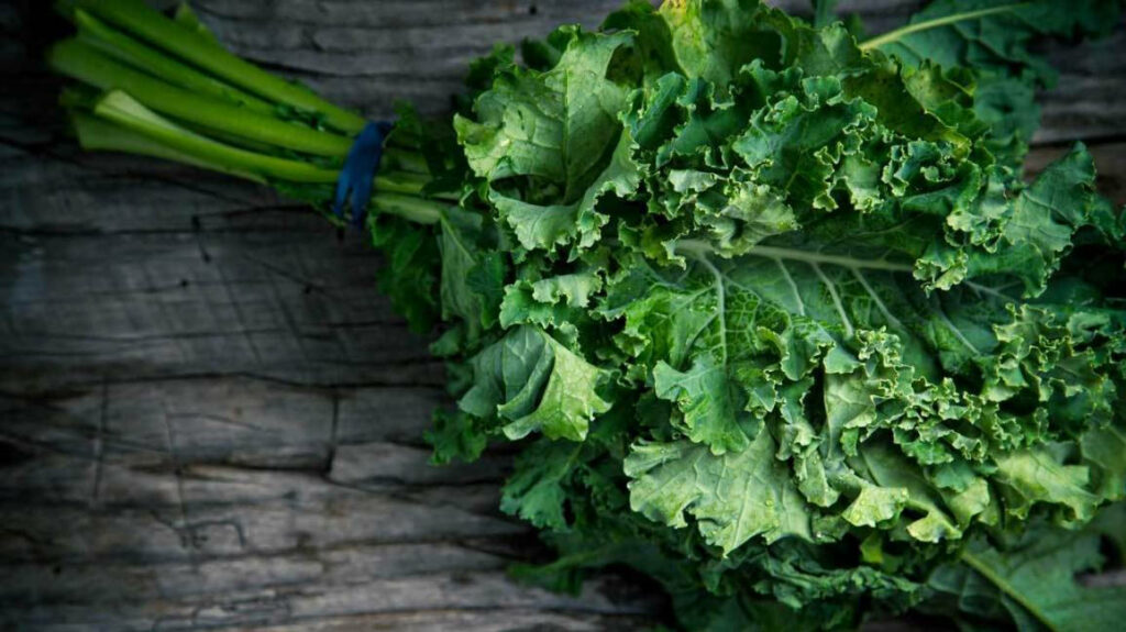 Rustic Kale Wallpaper: Organic Green Leaves on Wooden Surface Background