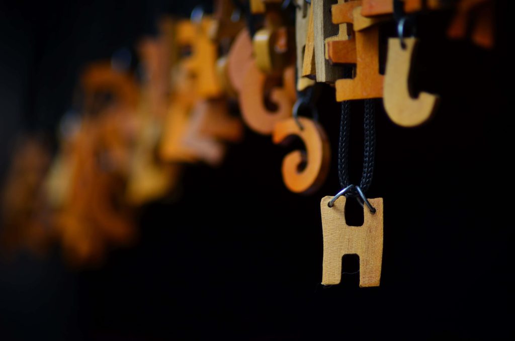 Macro photo of rustic wooden letter H pendant with blurred wooden letters background Wallpaper