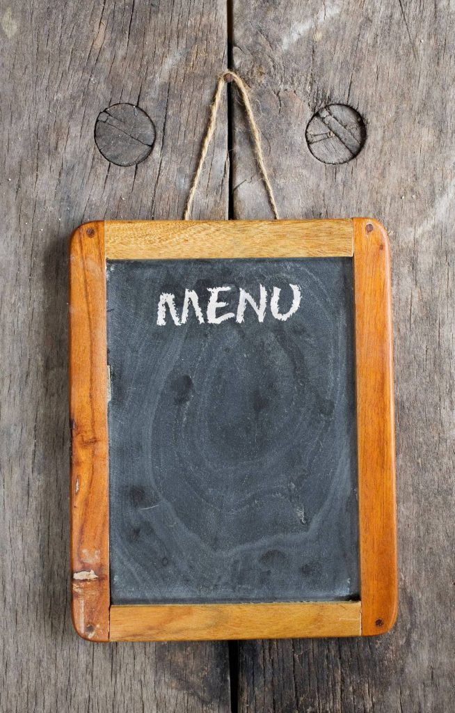 Rustic wooden menu board with blank chalkboard on weathered timber wallpaper background