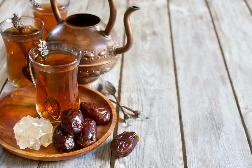 Rustic wooden table with copper teapot red dates tea amber sugar crystals warm traditional scene Wallpaper