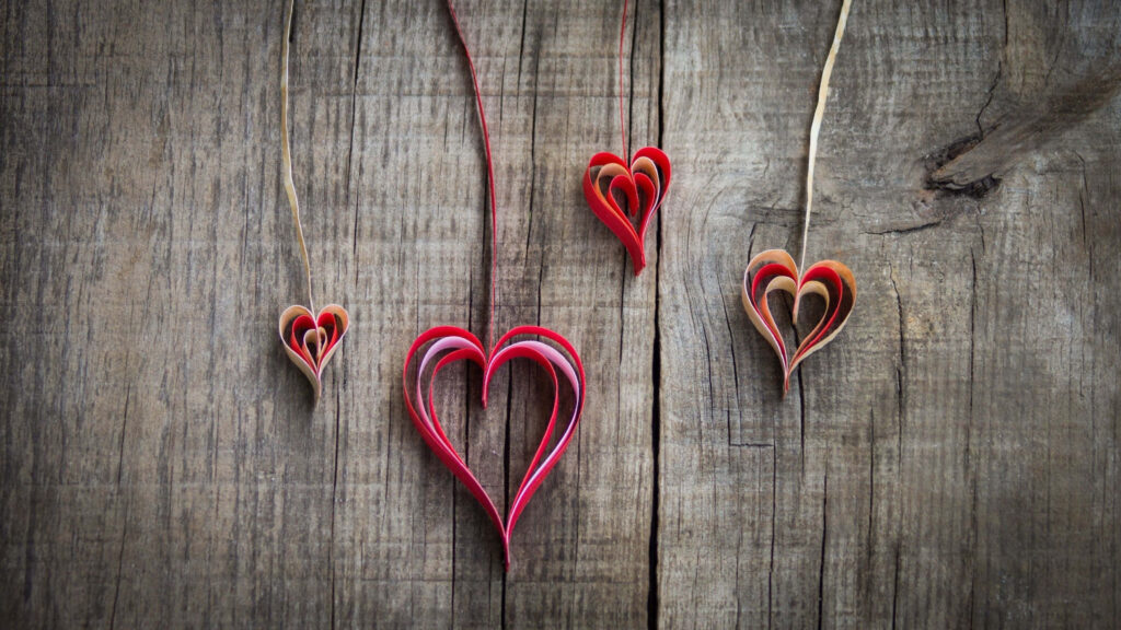 Charming Rustic Wooden Background with Hanging Heart Decorations Wallpaper
