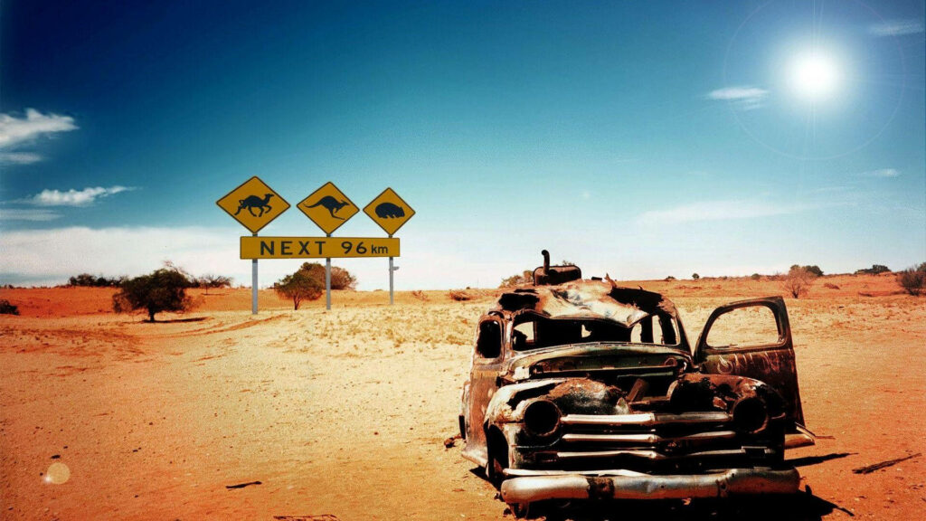 The Abandoned Cruiser: A High-Res Wallpaper of a Broken Car in the Desert