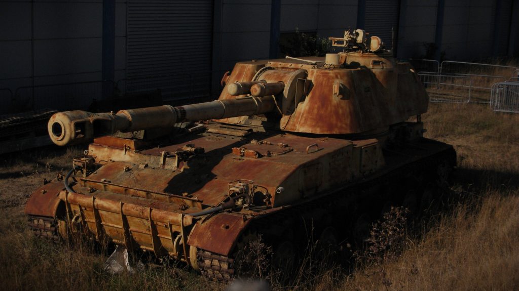 Rusty 2S3 Akatsiya self-propelled howitzer tank in dry grass cinematic military wallpaper background