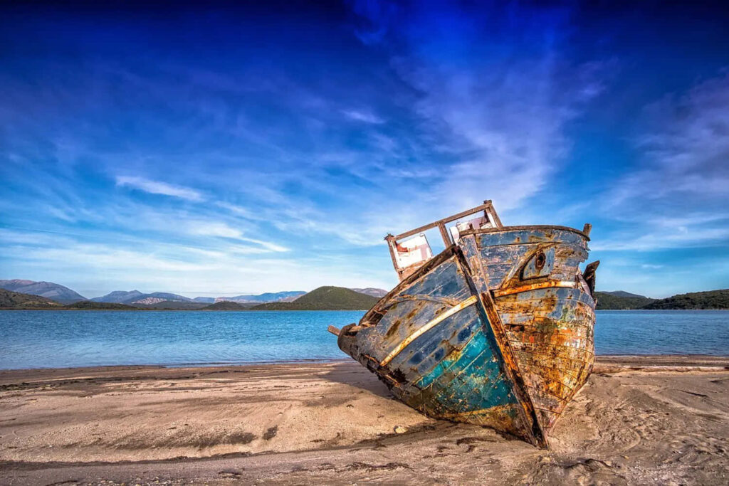 Rustic Boat by Tranquil Shoreline: Timeless Solitude Wallpaper