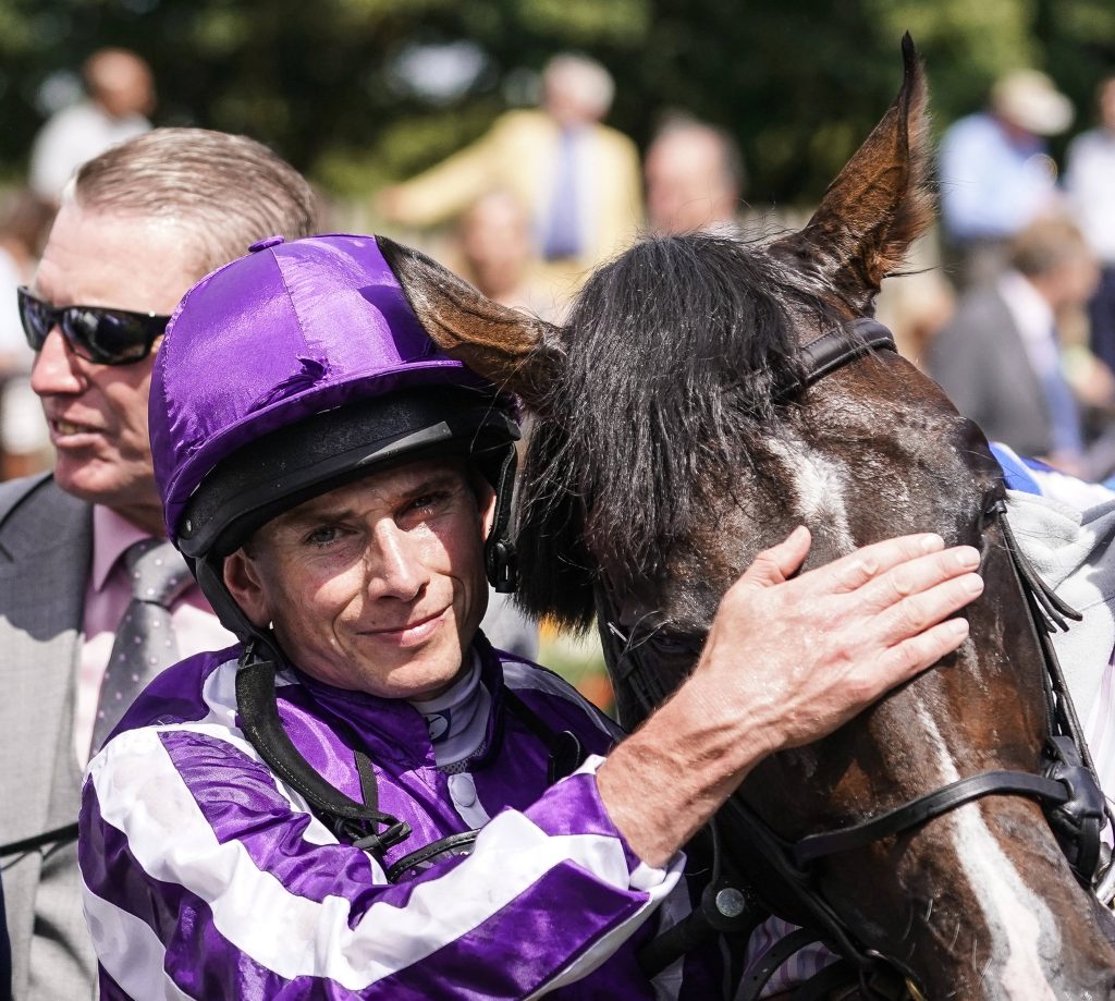 Jockey Ryan Moore in purple and white silks warmly embraces his racehorse race day bond Wallpaper