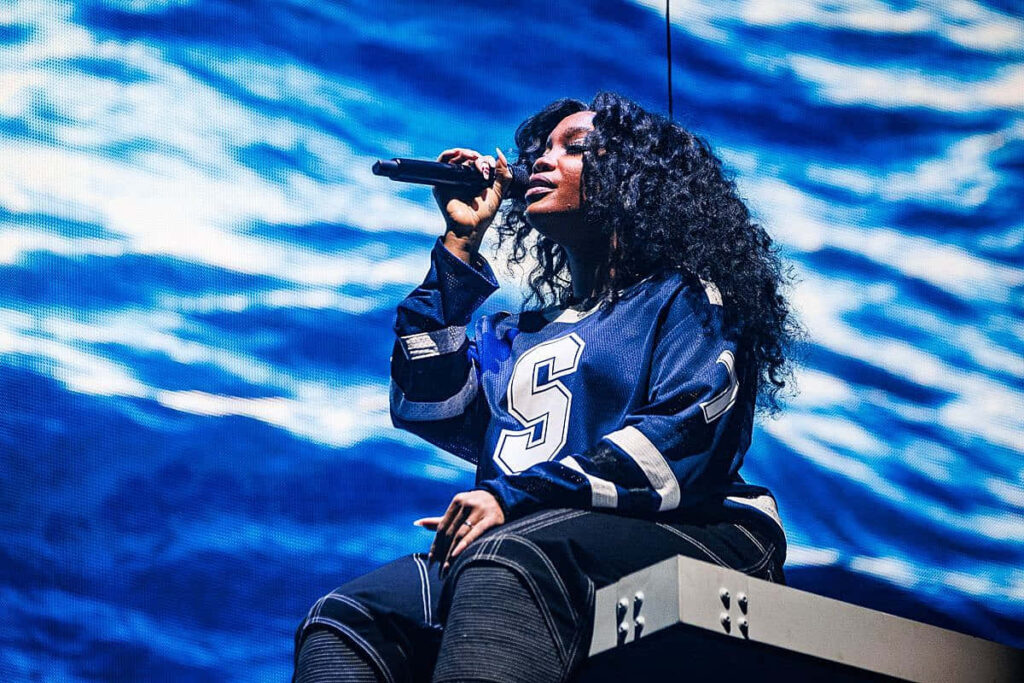 Stunning SZA Stage Performance Wallpaper with Blue Waves Backdrop