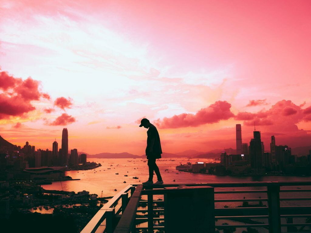 Lonely Boy Amidst the City Lights: Captivating Pink Twilight Wallpaper