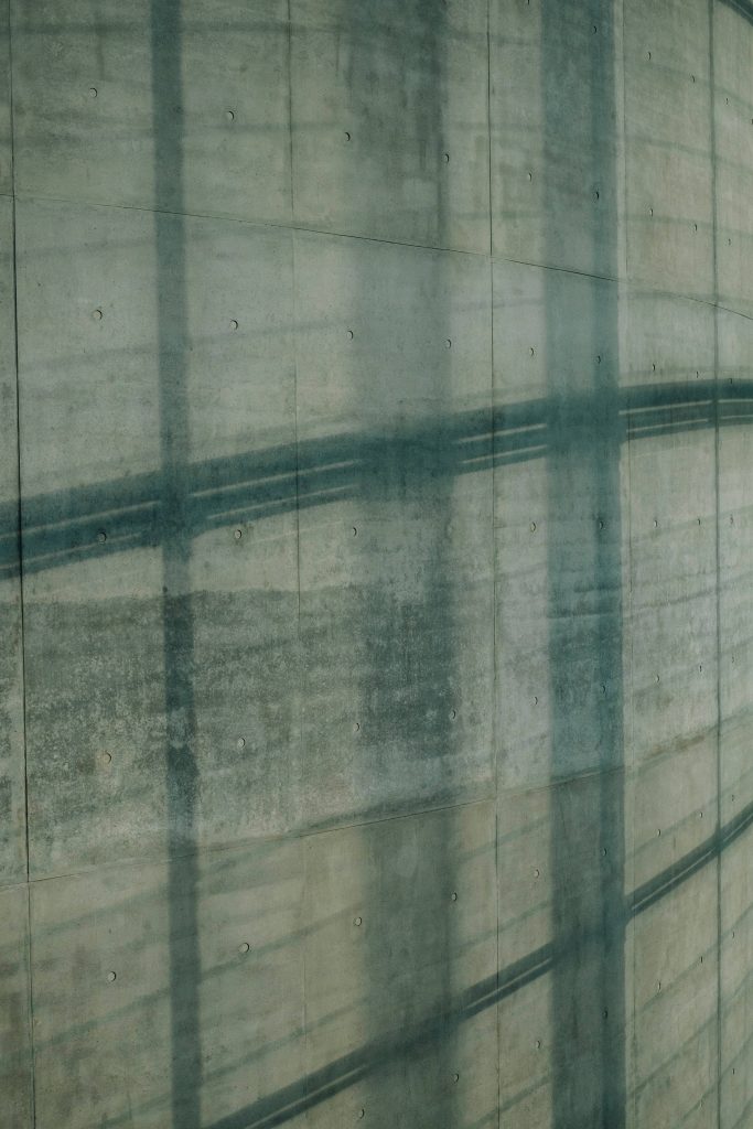 Sage green concrete wall wallpaper with geometric shadows and textured industrial minimalist design