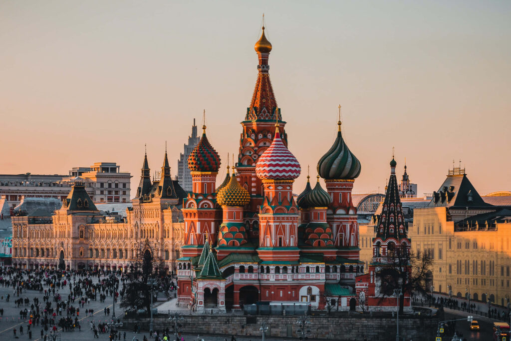 Saint Basil's Cathedral glowing at golden hour in Moscow with crowds and historic buildings Wallpaper