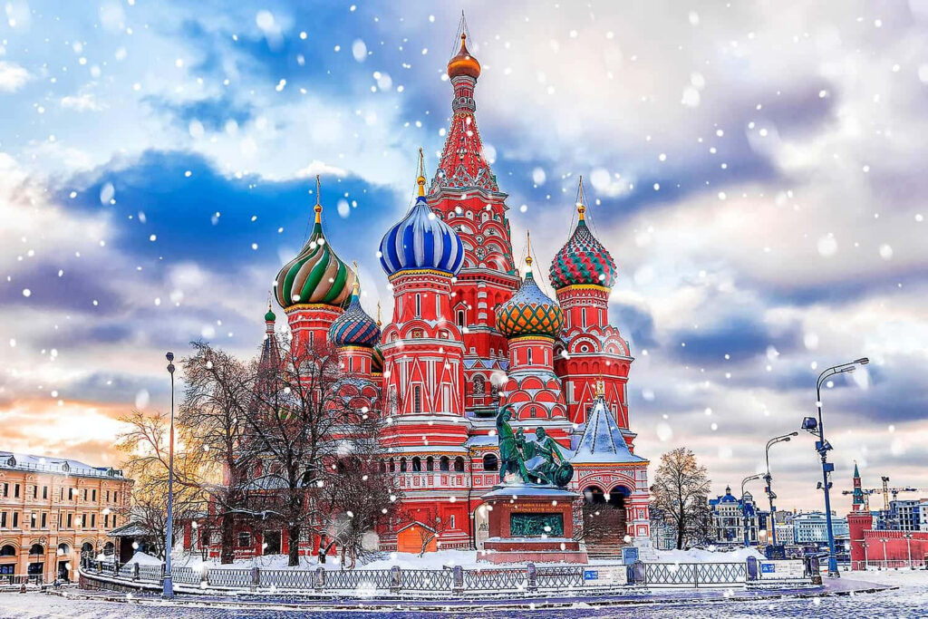 Saint Basils Cathedral in Moscow with vibrant domes covered in falling snow winter scene wallpaper