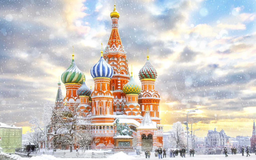 Saint Basils Cathedral in Moscow covered in snow with colorful onion domes and falling snowflakes Wallpaper