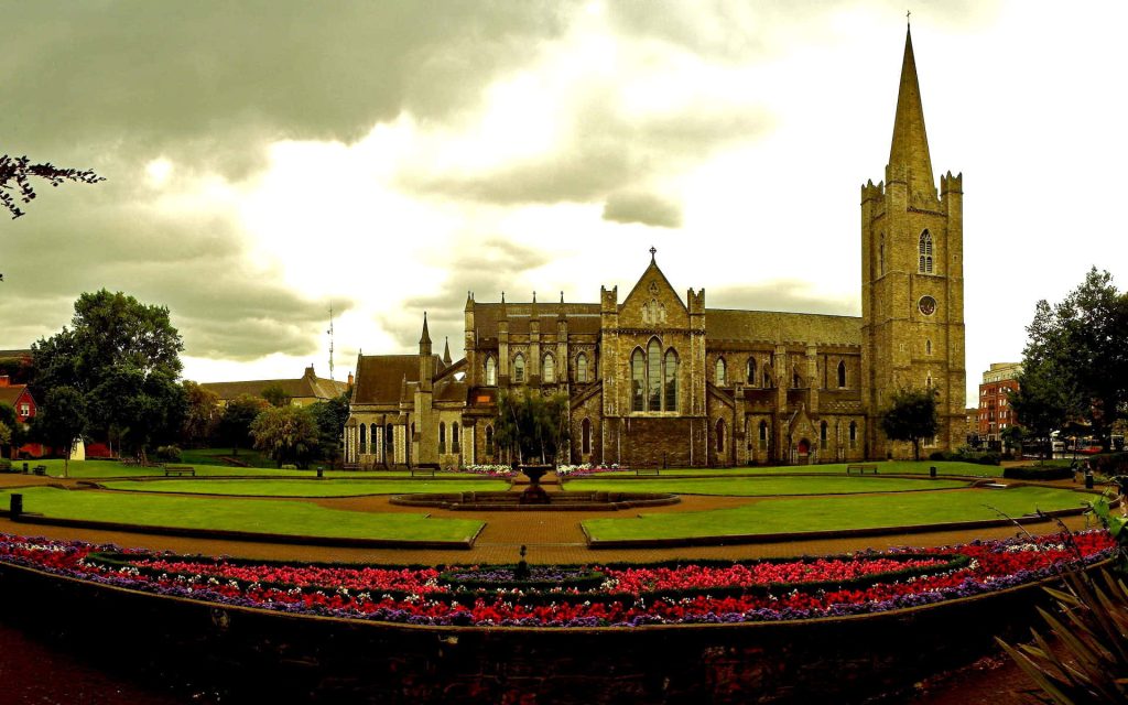 Saint Patricks Cathedral Dublin stone architecture spire park flowers overcast sky wallpaper