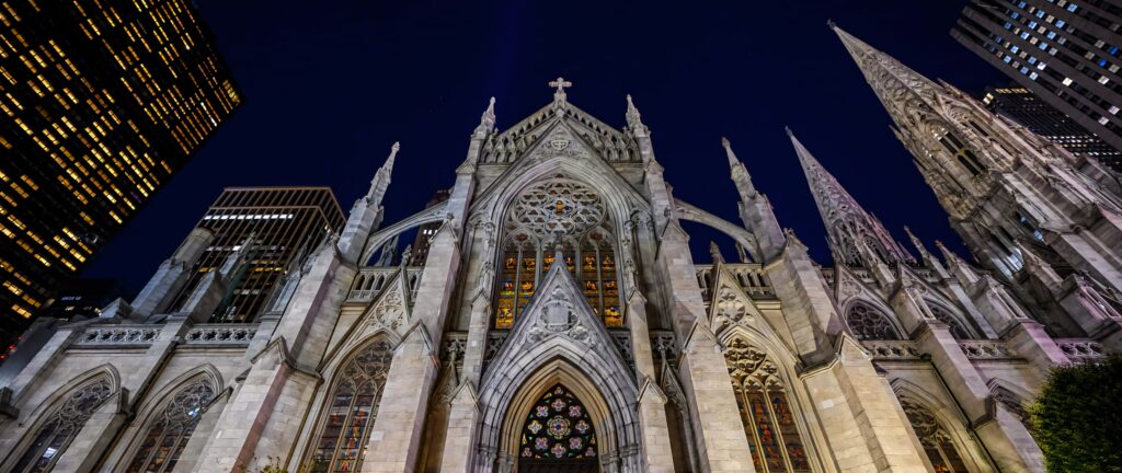 Saint Patricks Cathedral illuminated at night showcasing Gothic architecture and stained glass windows Wallpaper