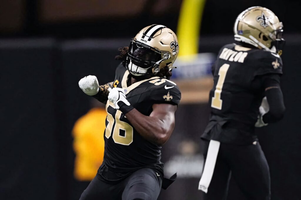 Saints linebacker Demario Davis celebrates in black and gold uniform with teammate under stadium lights Wallpaper