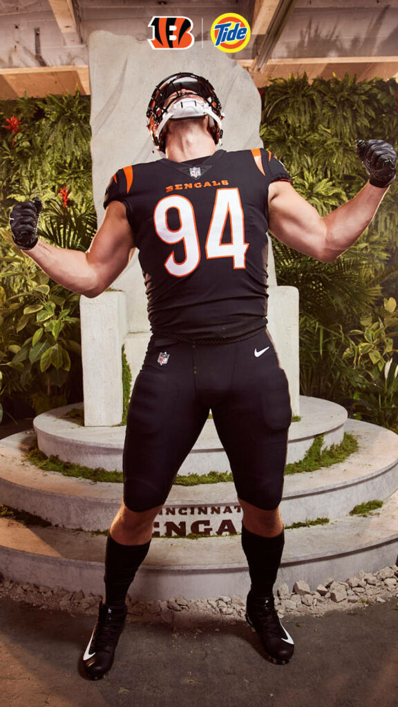 Sam Hubbard Cincinnati Bengals in uniform powerful pose with Bengals and Tide logos on green background Wallpaper