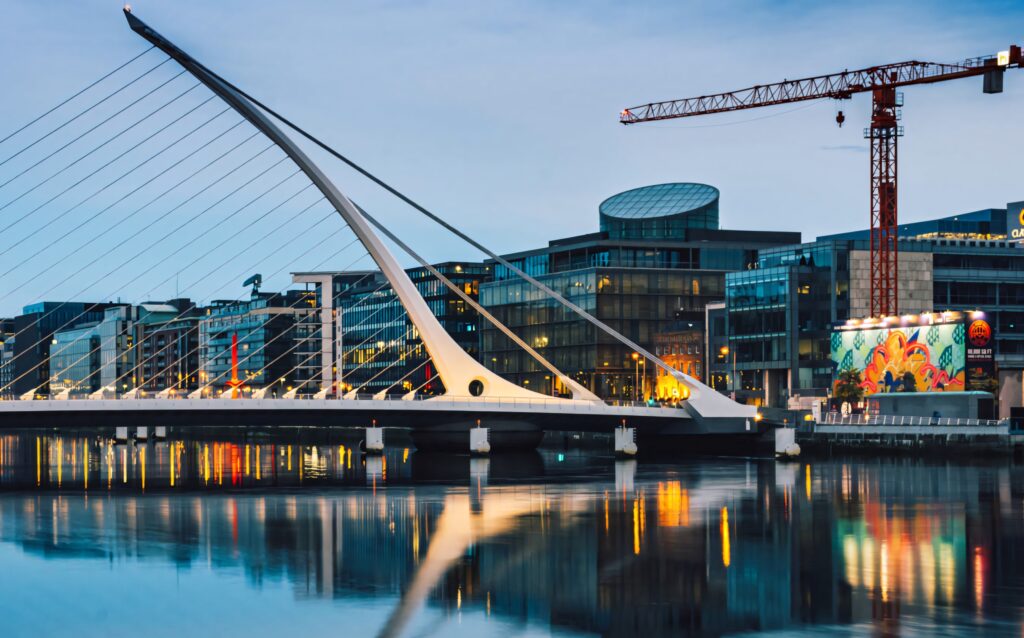 Samuel Beckett Bridge in Dublin harp shape reflected on river with cityscape and mural background Wallpaper