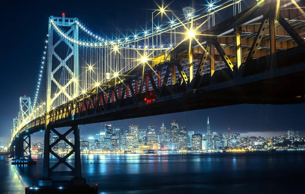 San Francisco skyline at night with glowing Bay Bridge and water reflections wallpaper background