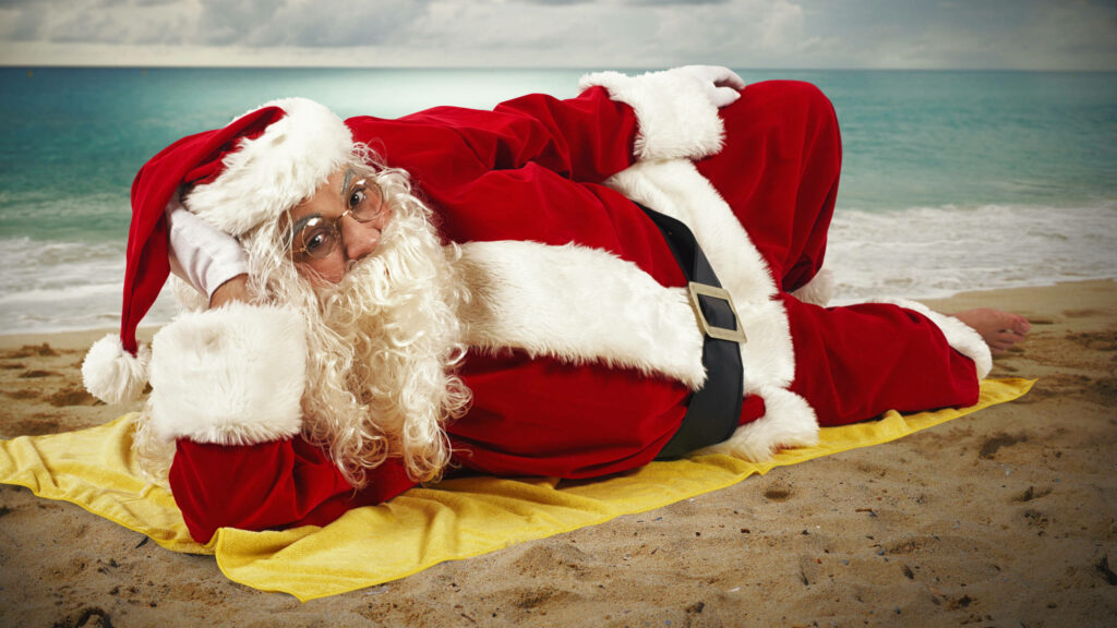 Santa Claus on Sandy Beach: Holiday Charm Meets Tropical Relaxation Wallpaper