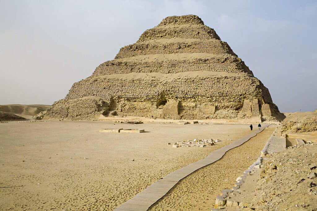 Side view of Saqqara Pyramid ancient limestone steps desert pathways clear sky wallpaper