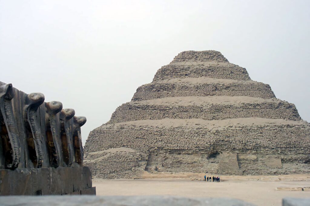Ancient Saqqara Pyramid with stepped stone structure and abstract serpent sculptures desert wallpaper