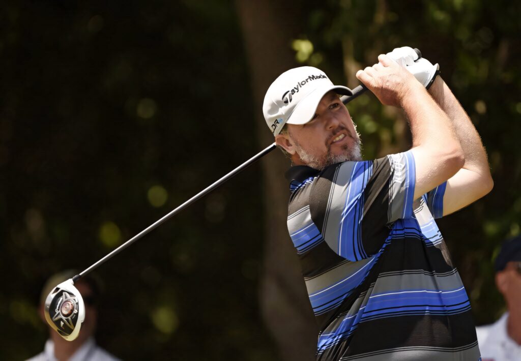 Boo Weekley golf swing on course in striped shirt and cap with sunlight sports wallpaper background