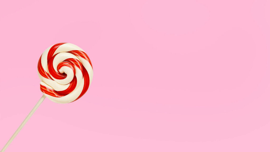 Satisfy Your Sweet Tooth with Minimalist Red Candy on Pastel Pink Wallpaper