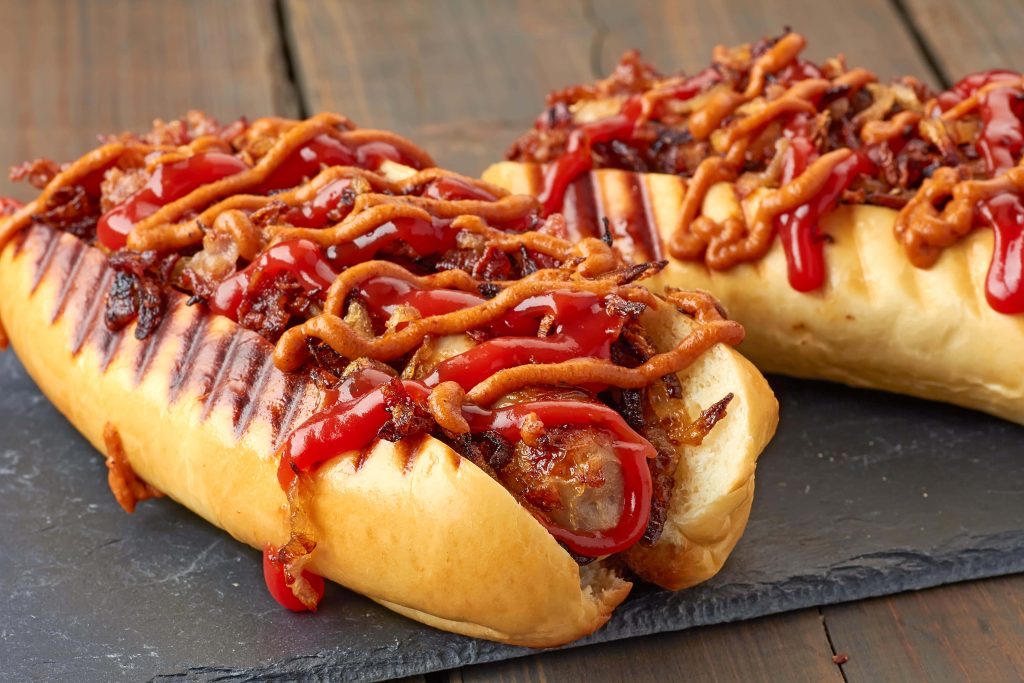 Two savory hot dogs with crispy onions ketchup and mustard on toasted buns on slate board Wallpaper