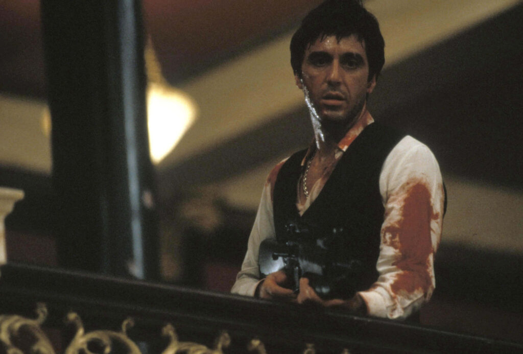 Scarface holding iconic weapon intense scene classic film dramatic wallpaper background