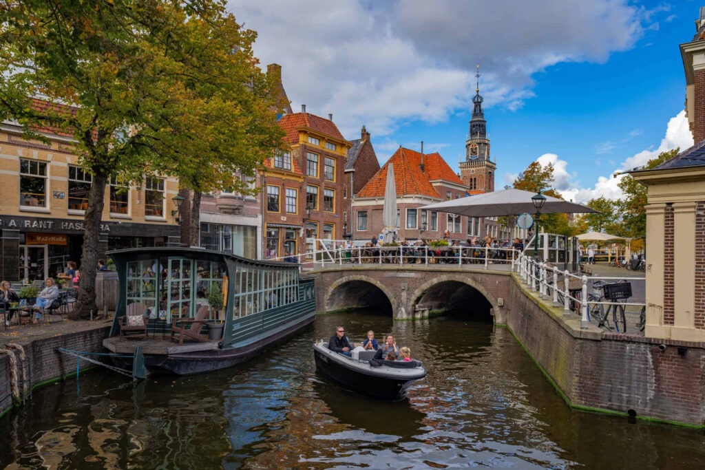 Scenic Alkmaar canal with historic Dutch buildings and boat cruising through charming town Wallpaper