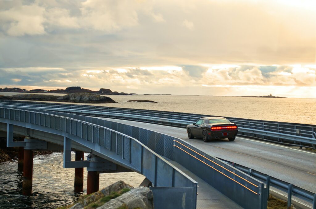 Serene Car Journey Over Sleek Bridge: Scenic Ocean Background Wallpaper
