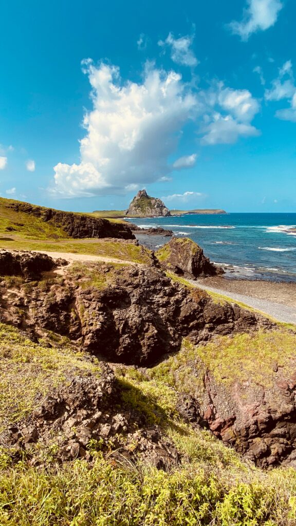 Scenic coastal landscape with rocky cliffs green grass mountains and blue sky with clouds wallpaper