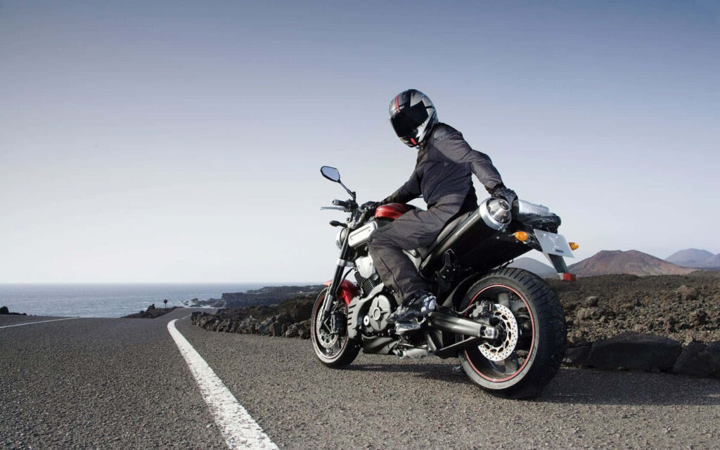 Scenic Coastal Road: Motorcyclist Wallpaper with Ocean Views