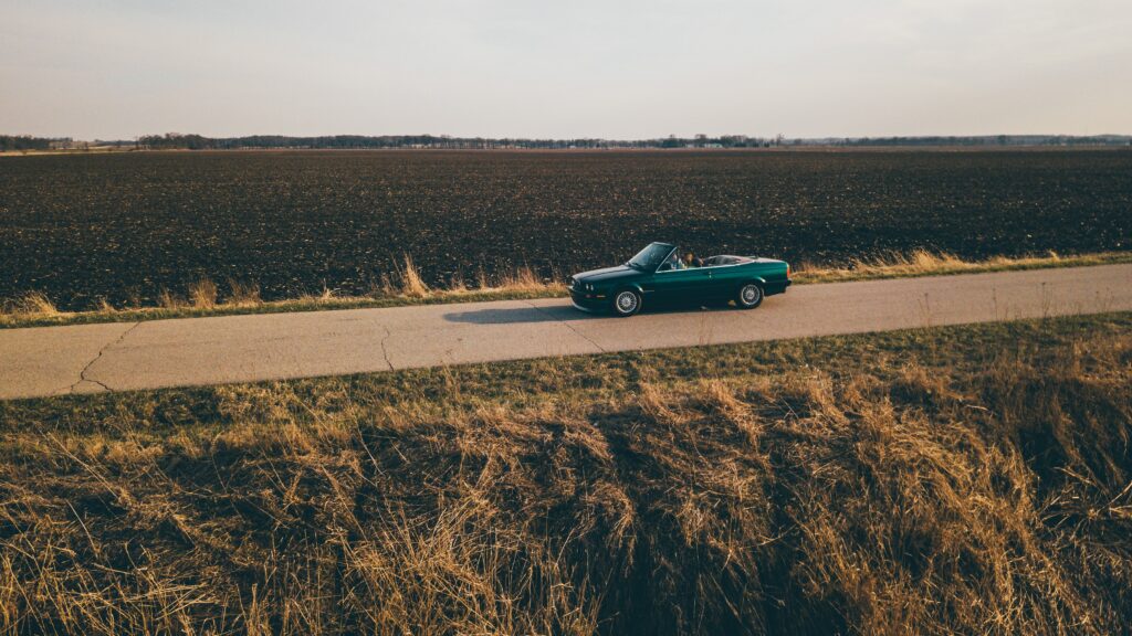 Serene Countryside Wallpaper: Convertible Adventure Over Vast Fields