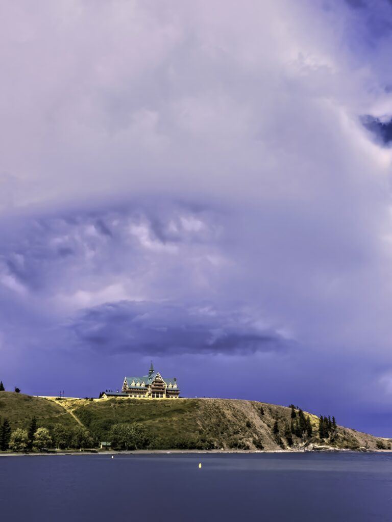 Grand building with green rooftops on island hill surrounded by tranquil sea and dramatic sky Wallpaper