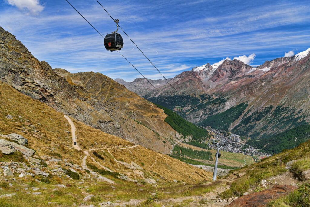 Cable car over golden slopes and rugged mountains with valley and cabin under blue sky view Wallpaper