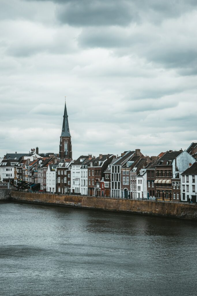 “Serene Riverside Town Wallpaper: Historic Buildings & Towering Spire”
