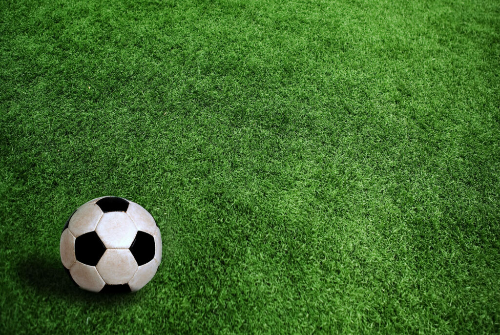 Black and white soccer ball on vibrant green turf wallpaper perfect for football fans