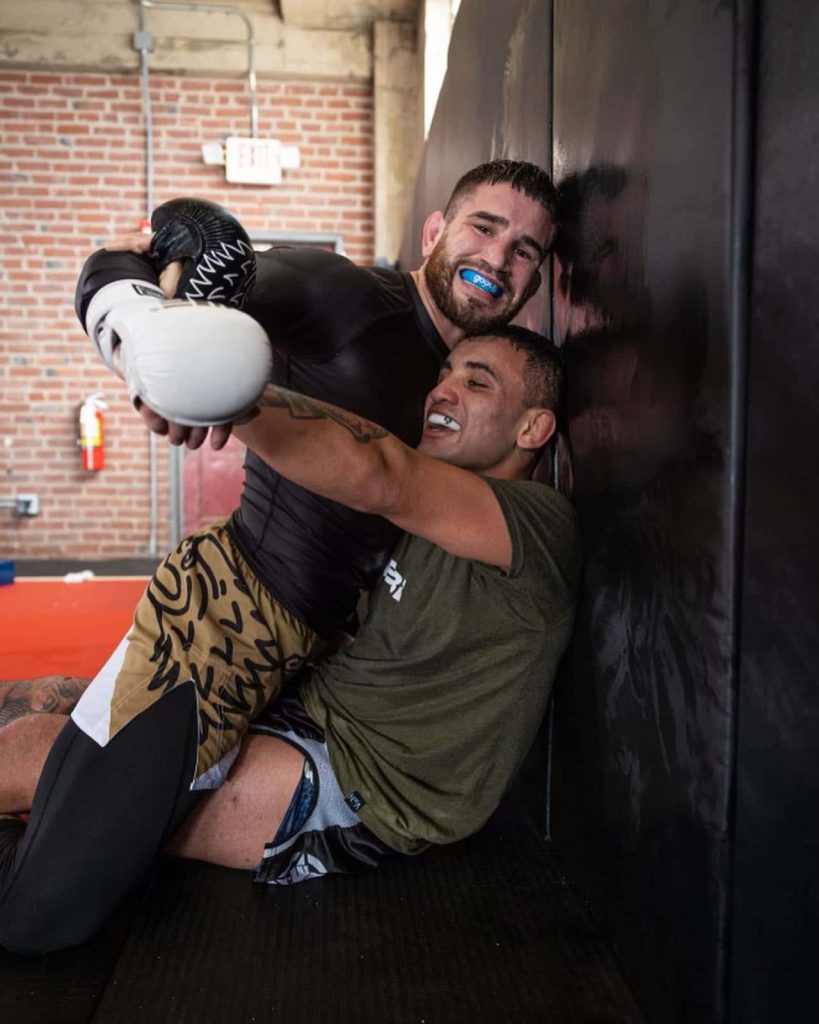 UFC fighters Sean Brady and Belal Muhammad training grappling in MMA gym with mouthguards Wallpaper