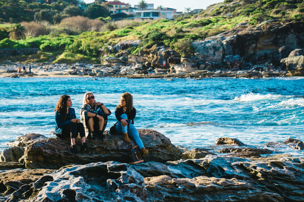A Serene Getaway at the Pebble Beach: Friends Enjoying Tranquility by the Shore Wallpaper