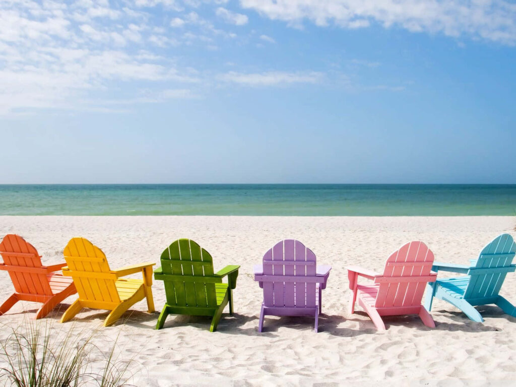 Coastal Charm: Rainbow Chairs Set against Blue Seas and White Sands in Spectacular Wallpaper